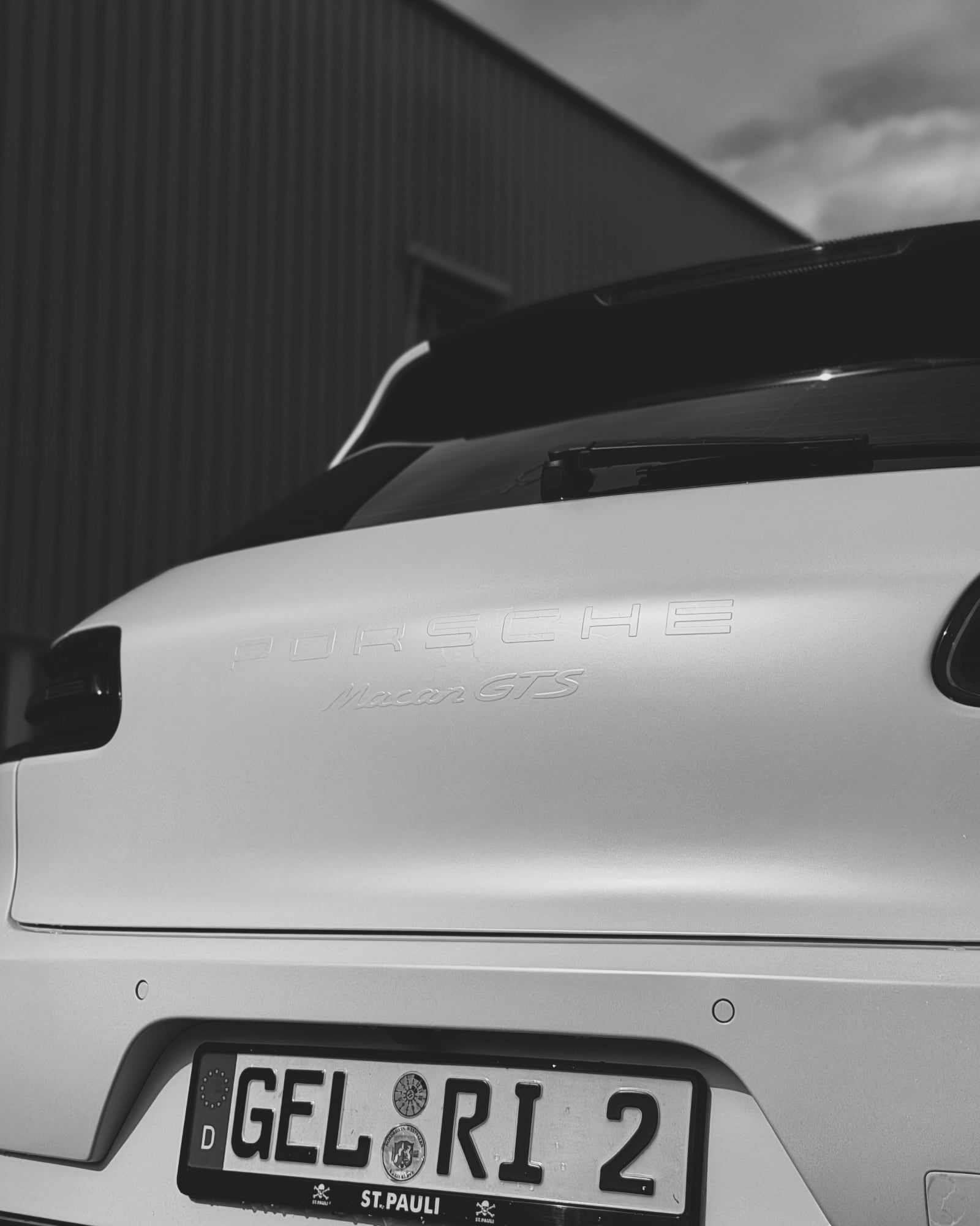 Detailaufnahme des folierten Heckspoilers eines weißen Porsche Macan